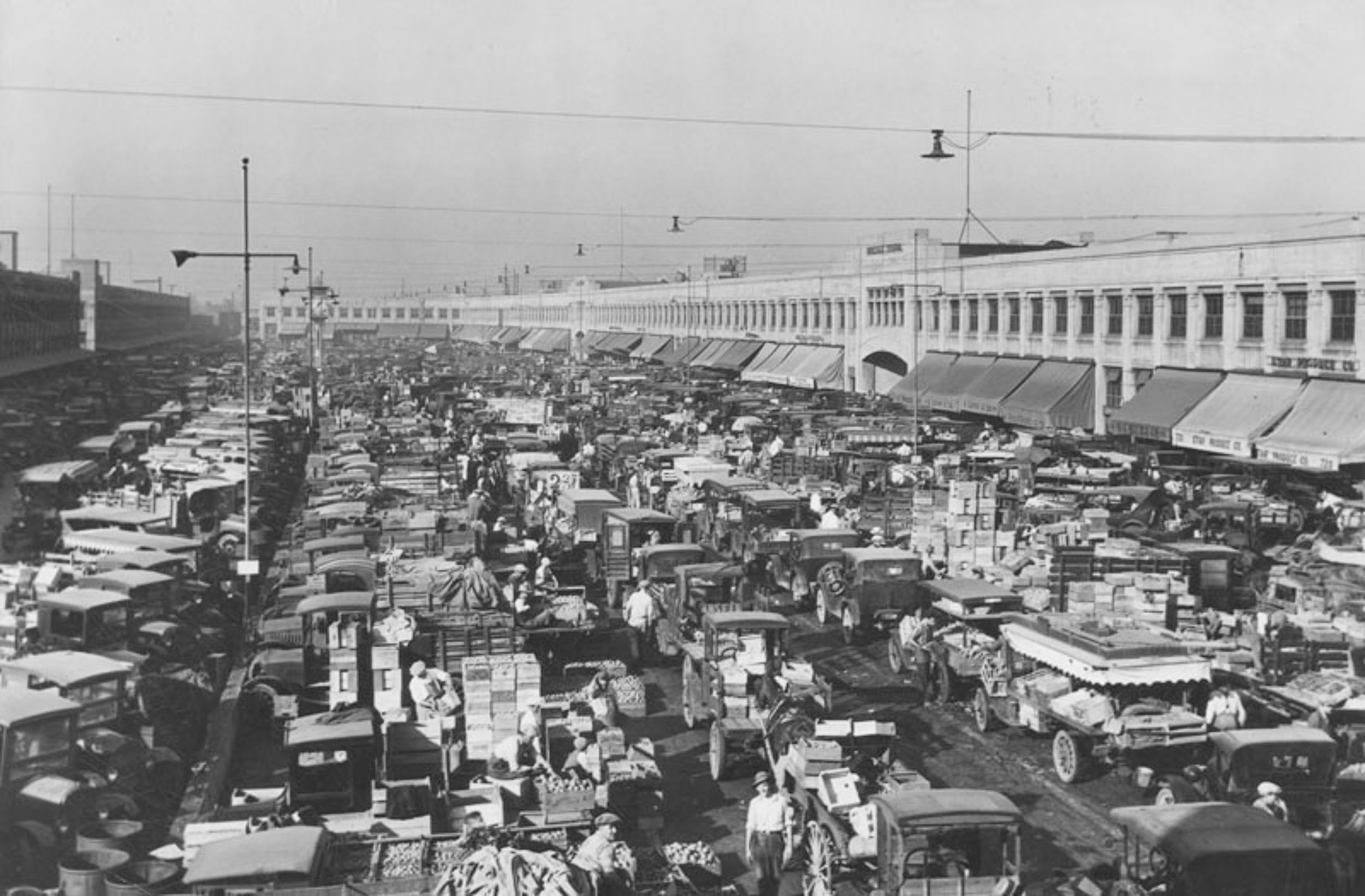 black and white picture of old cars bumper to bumper in the street