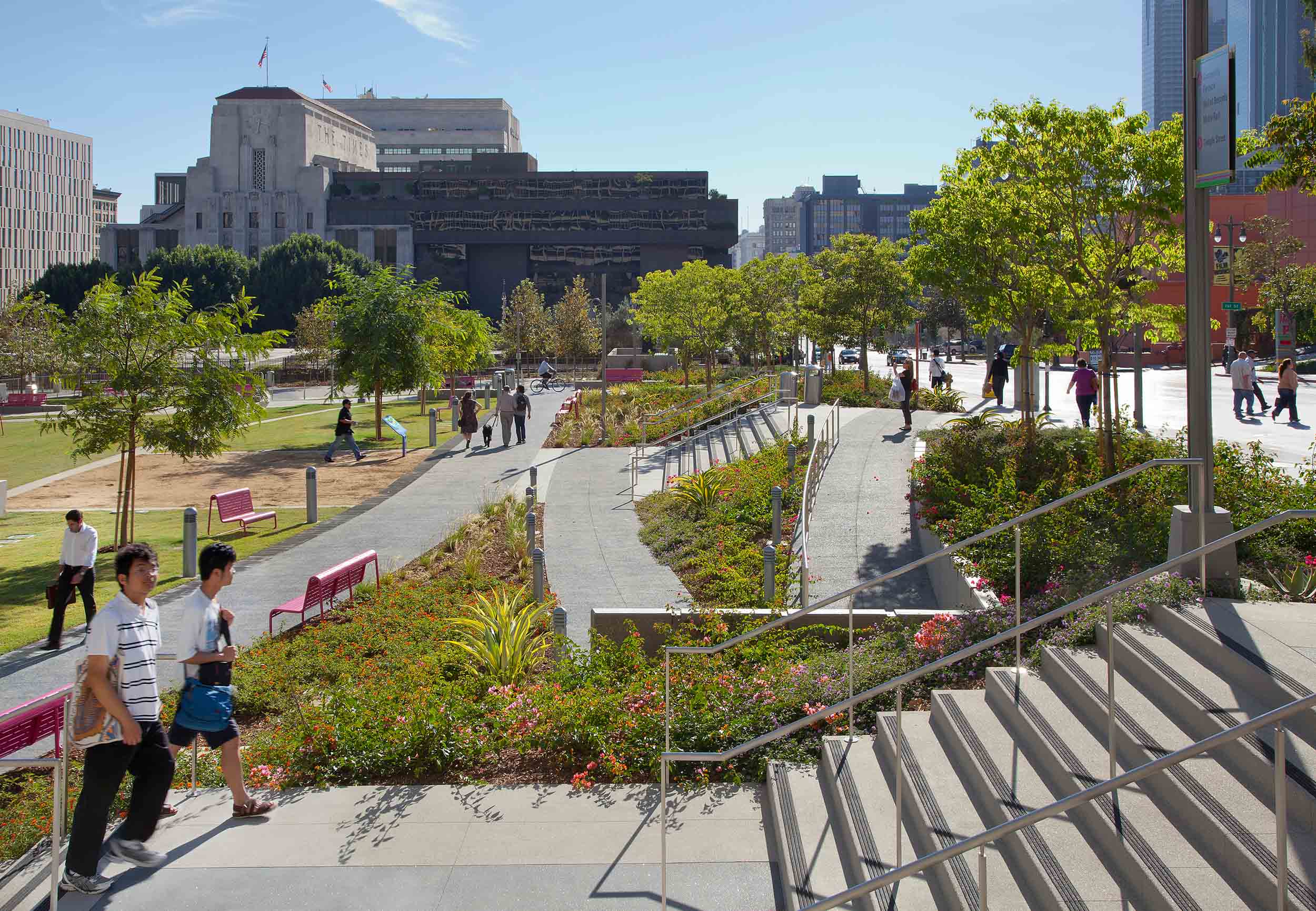 side view of people walking up stairs with intersecting curved paths in front of it, and plants along the sides of the stairs and paths