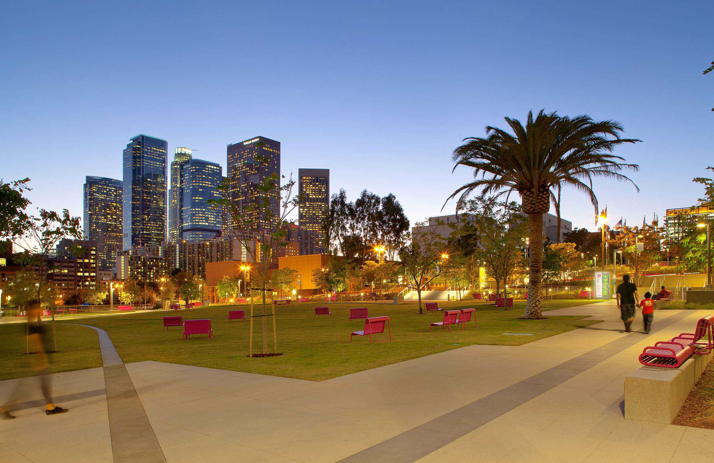 dusk shot of grand park lawn with pink seating and lit up buildings in the background