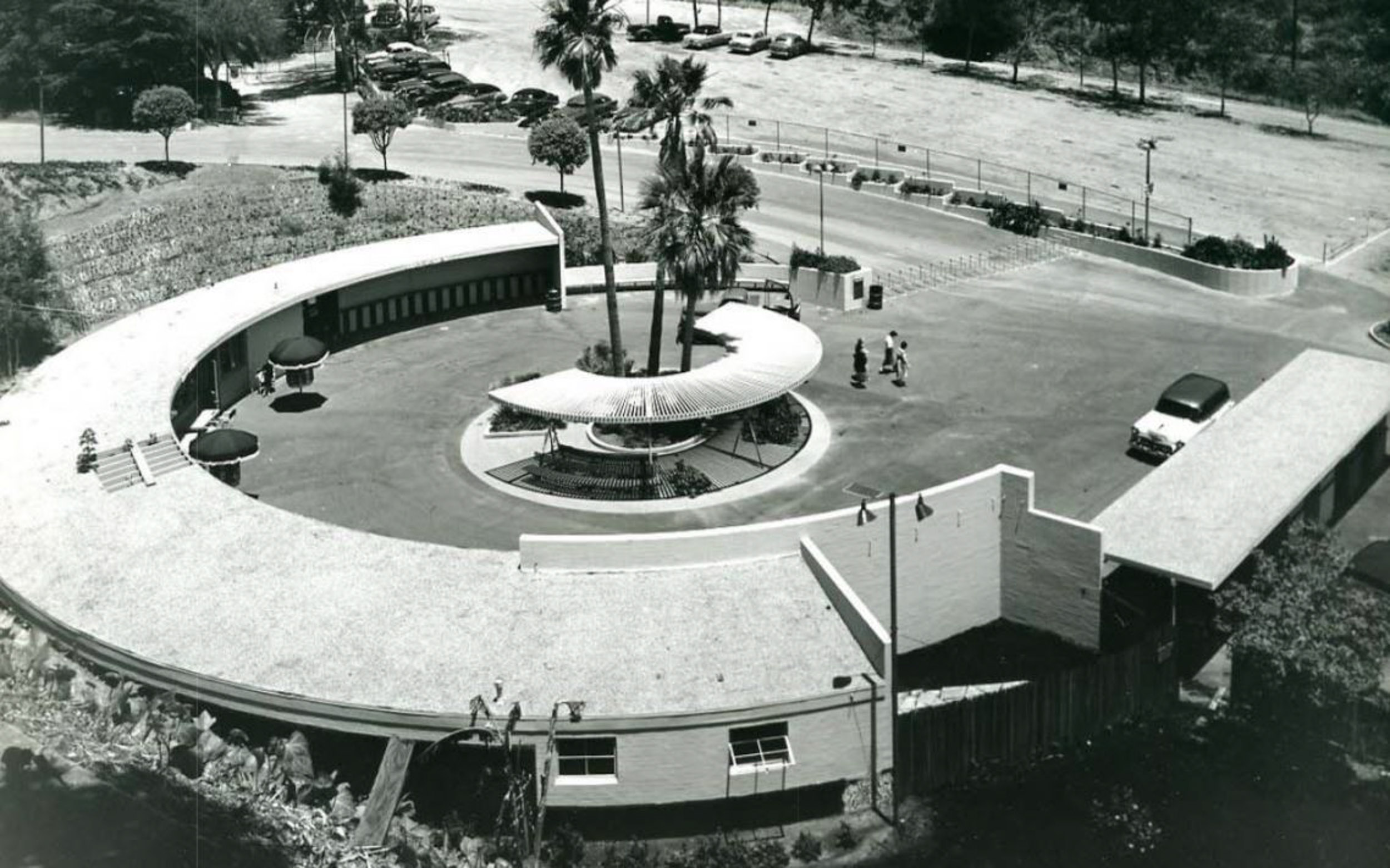 A black and white photo with a semicircular buildign and structure at the early H