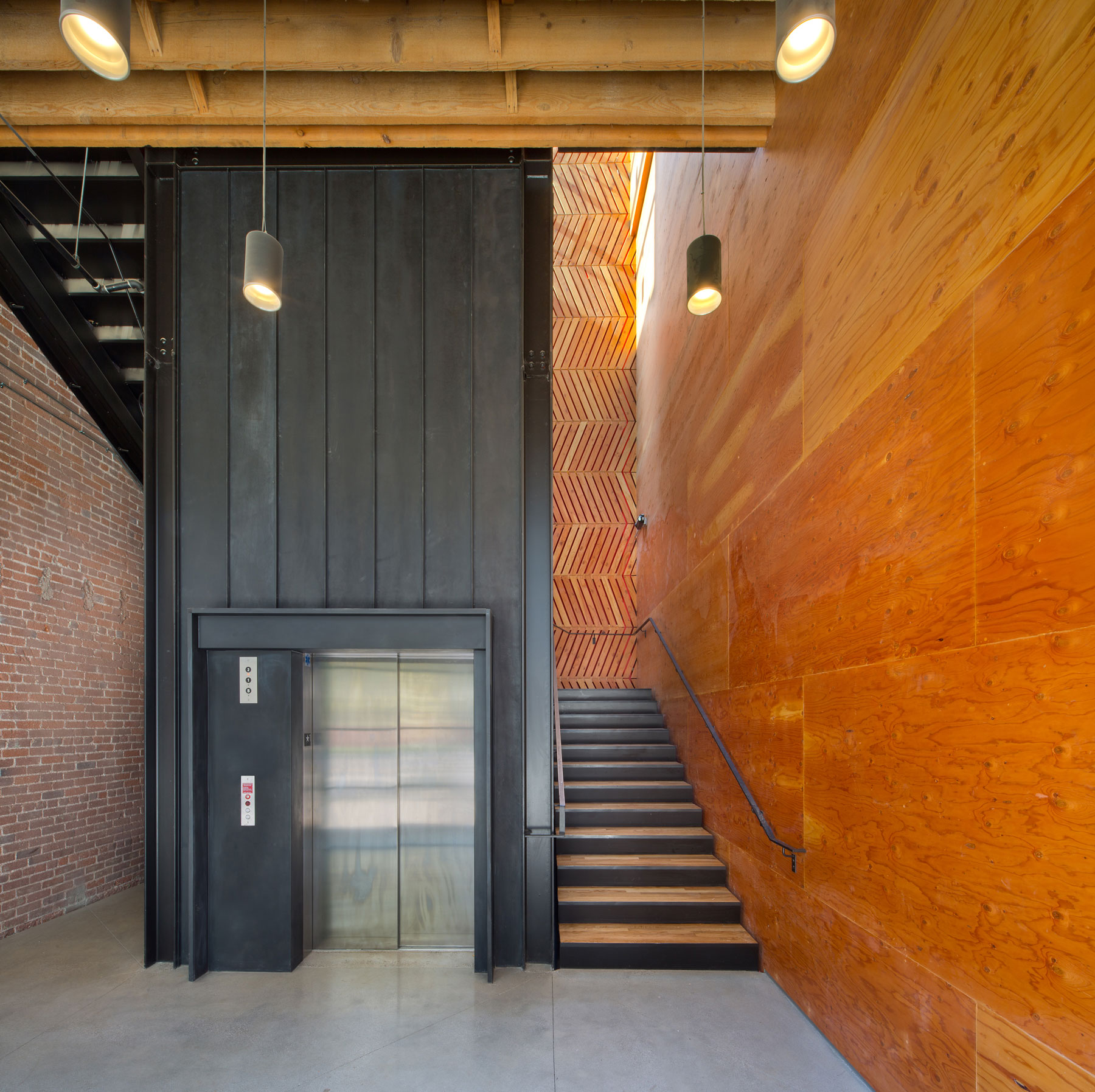 black wood elevator shaft with black stairs to the right, and wooden walls