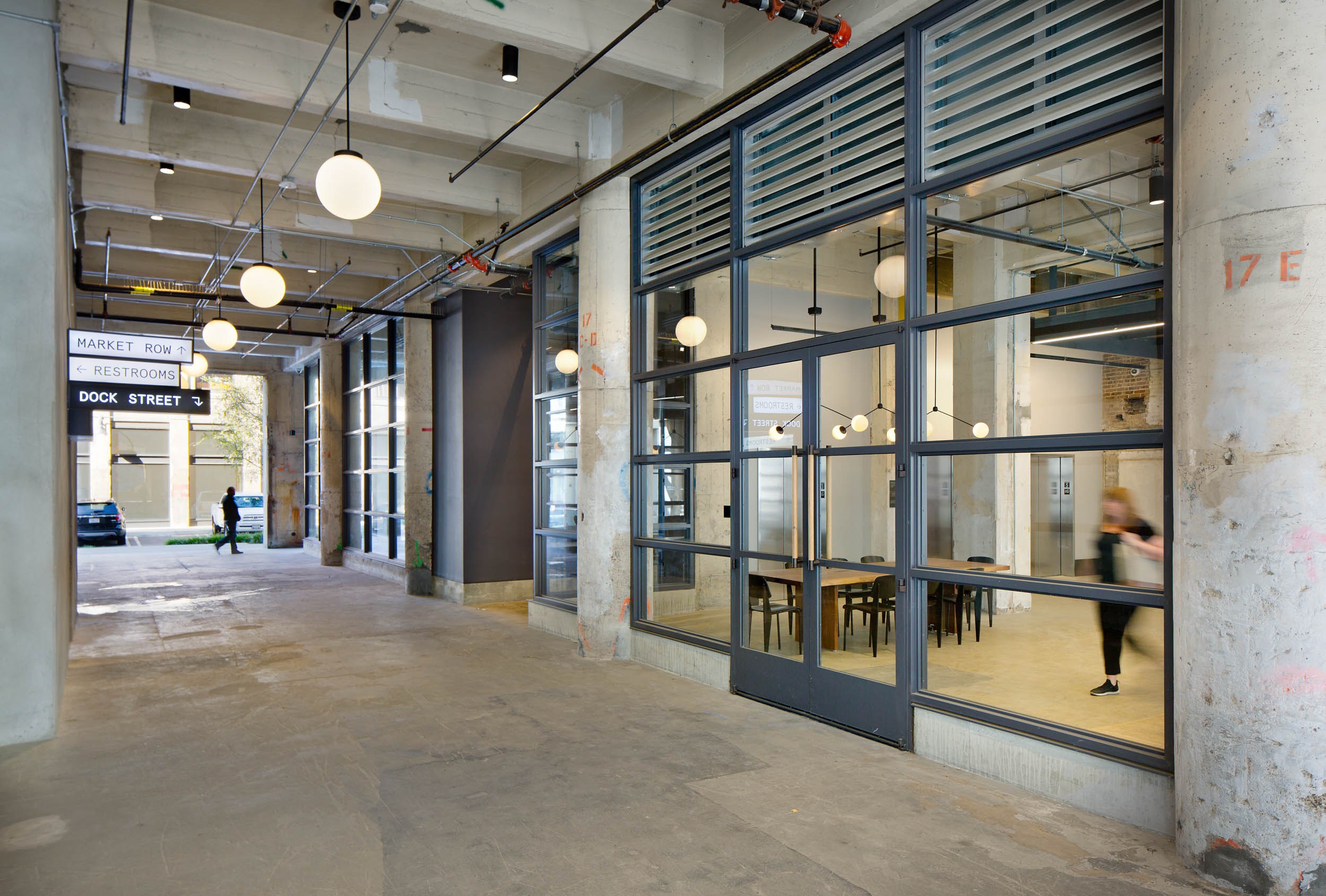 interior concrete breezeway with large windows and lights lining the ceiling