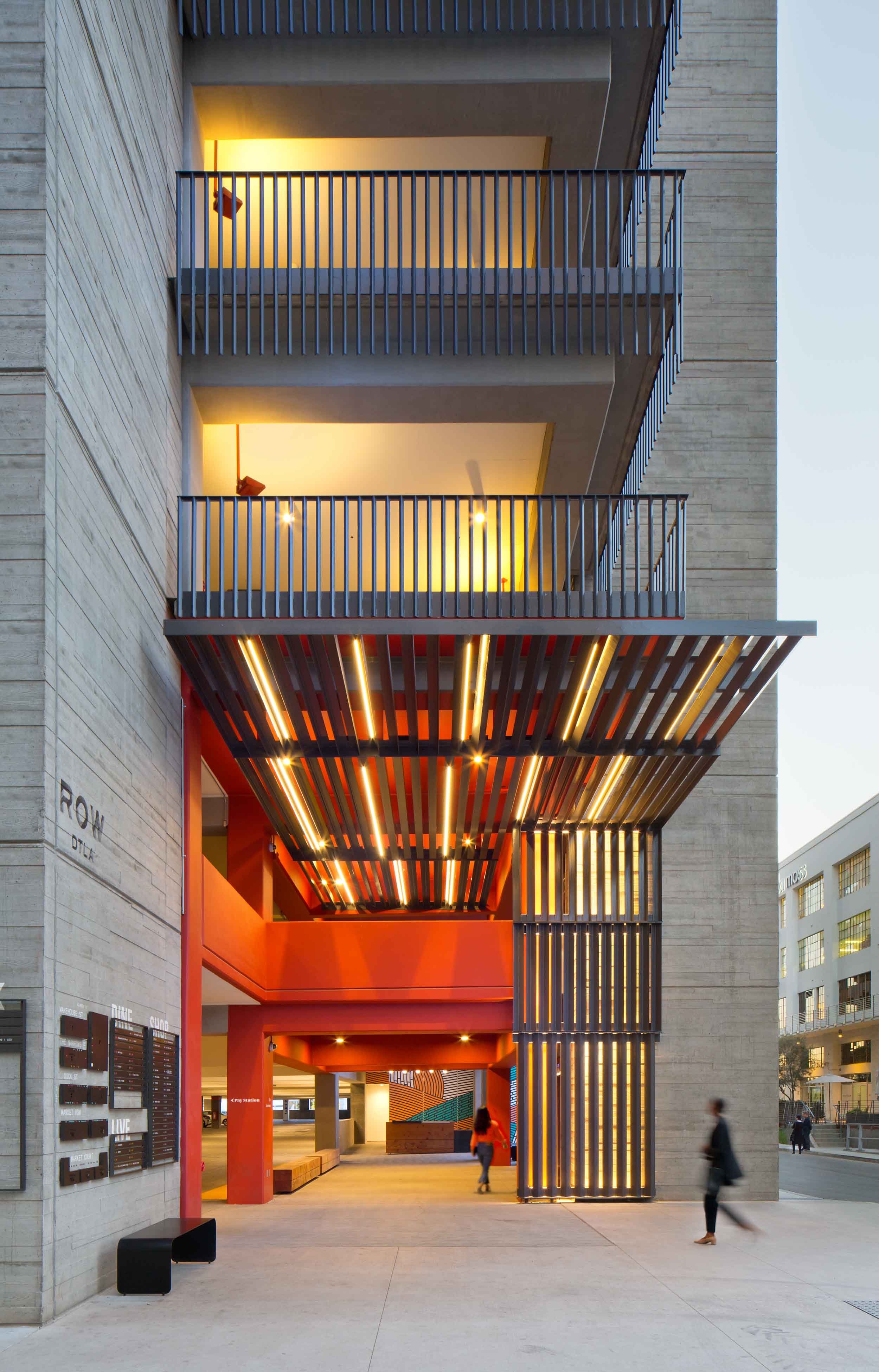 a building with a metal canopy showing a red interior, with balconies along the corner