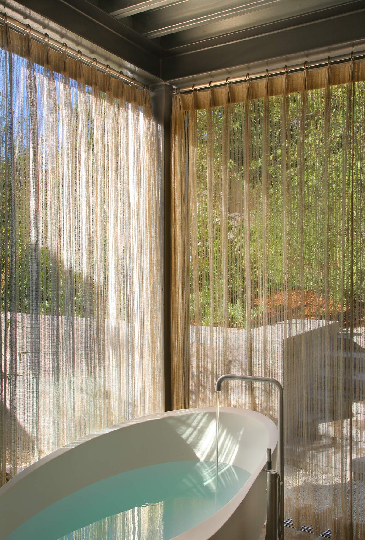 soaking tub behind sheer curtains