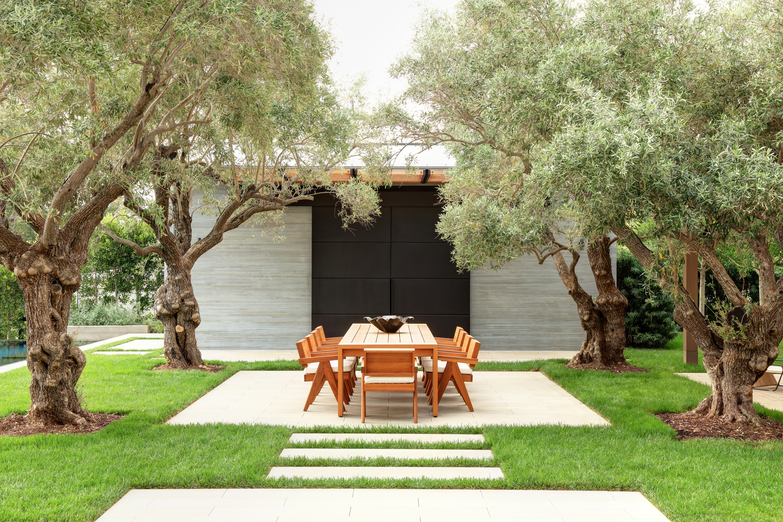 grass courtyard with central square cement floor and mature trees in each corner