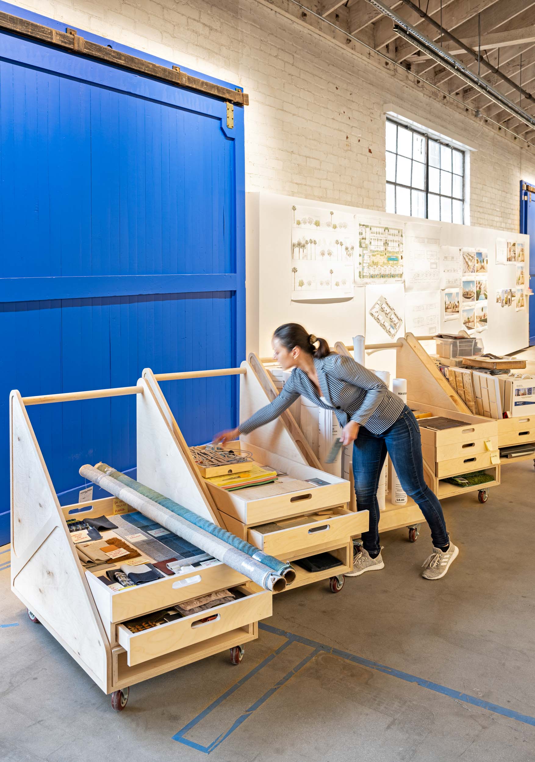 woman pulling from materials shelf in front of large blue barn doors