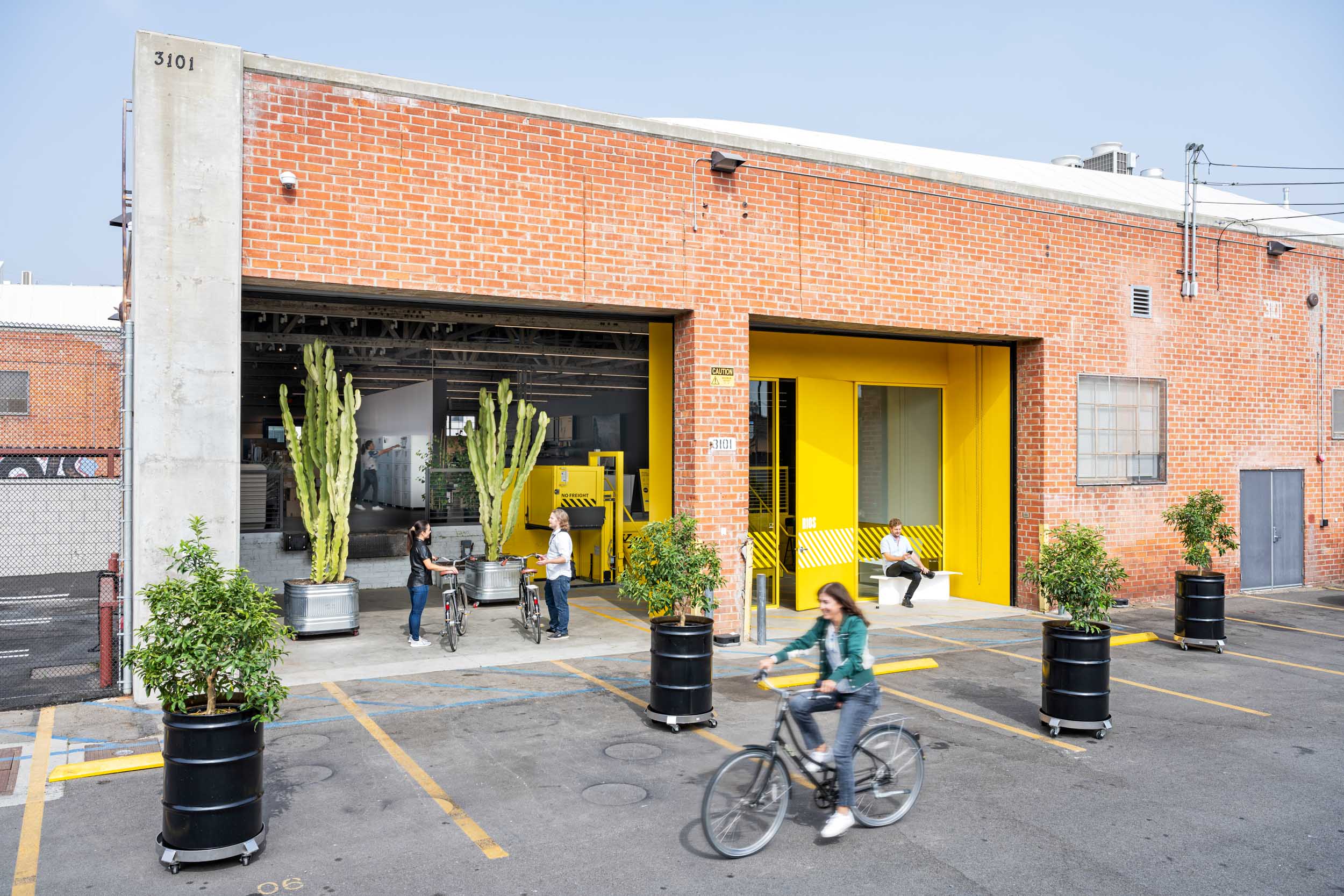 Exterior shot of the RIOS office with a woman riding her bike and cacti in the background