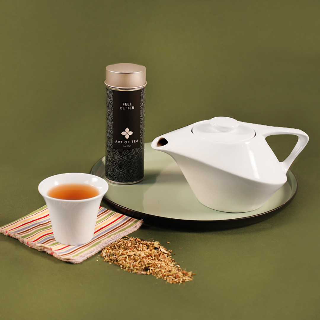 Tea cup and tea pot on a plate with dried tea leaves