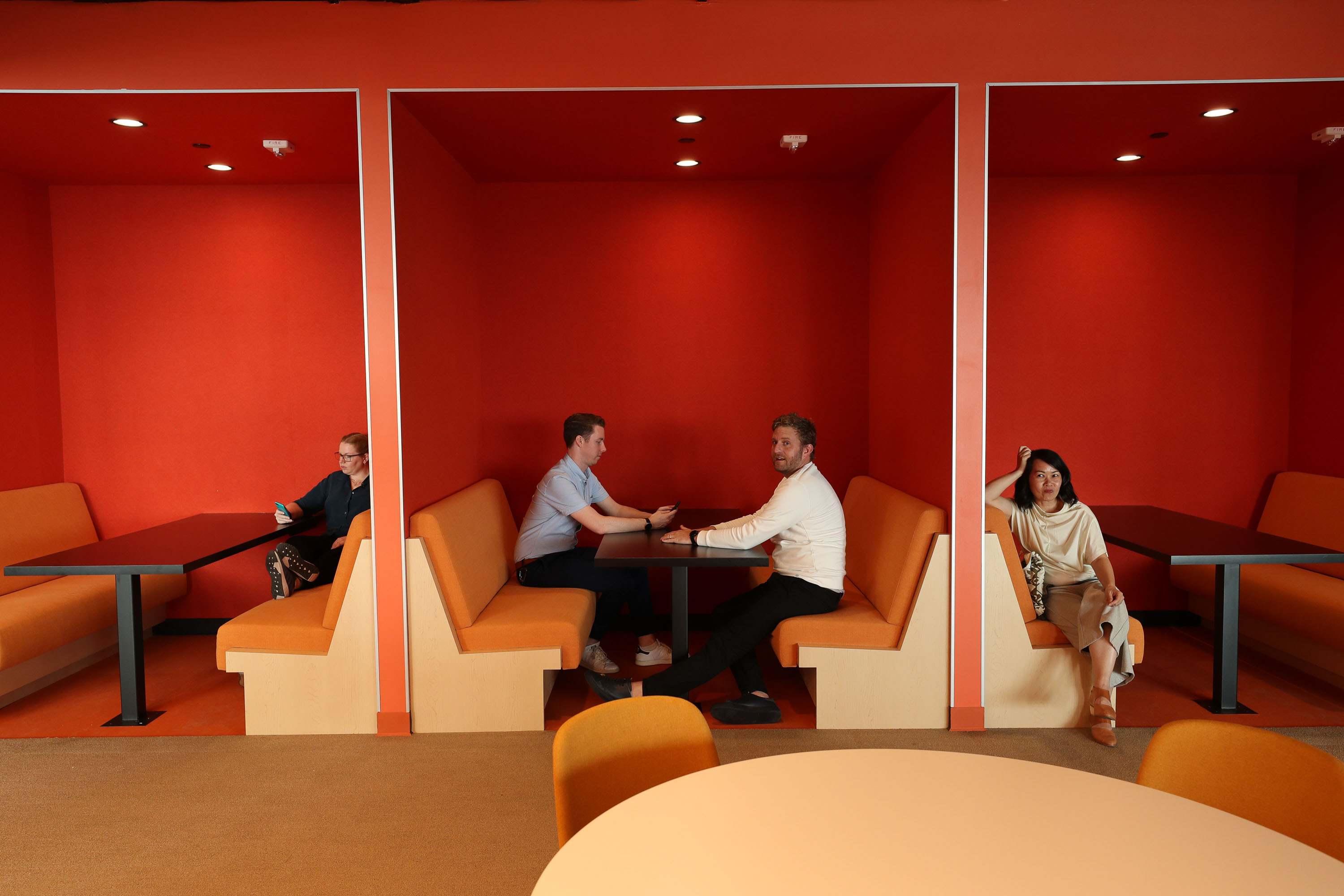 people sitting in orange booth seating with red walls