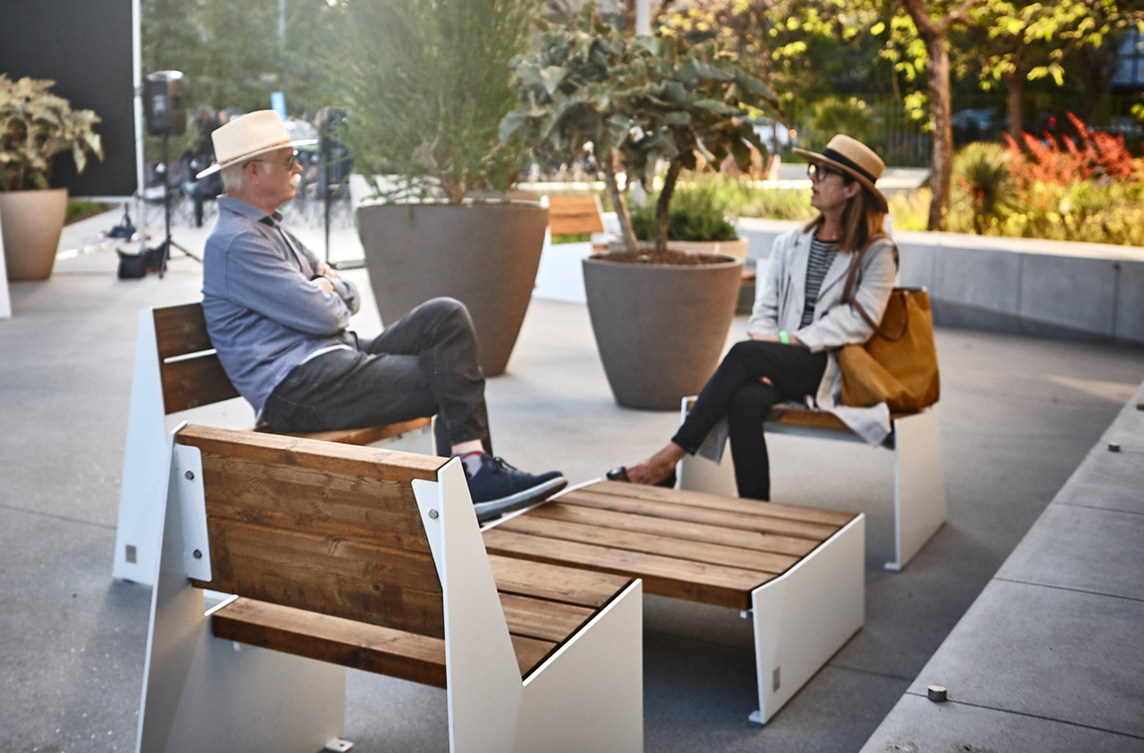 people seated on wooden furniture with planters behind them