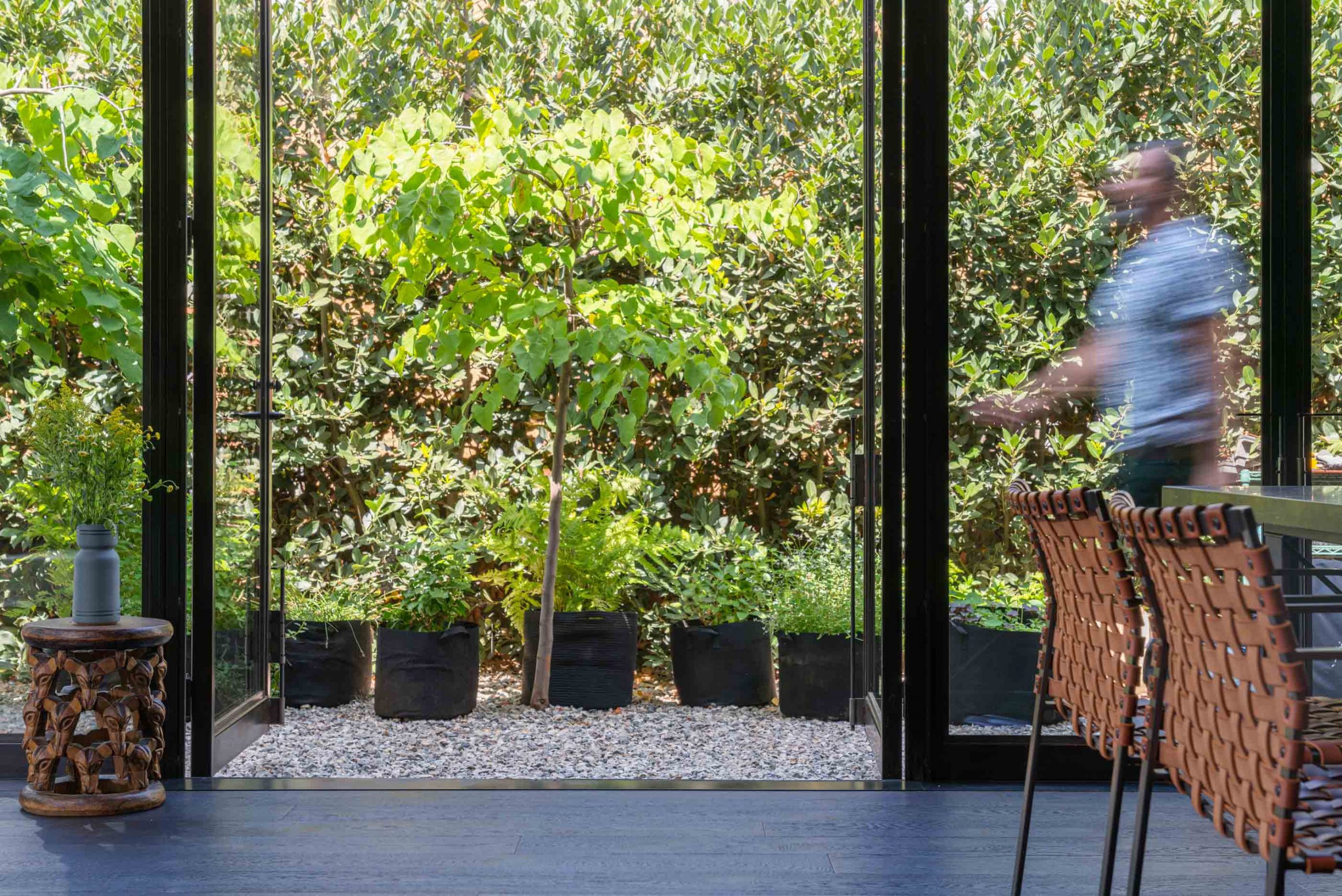 man walking past open glass door with plants