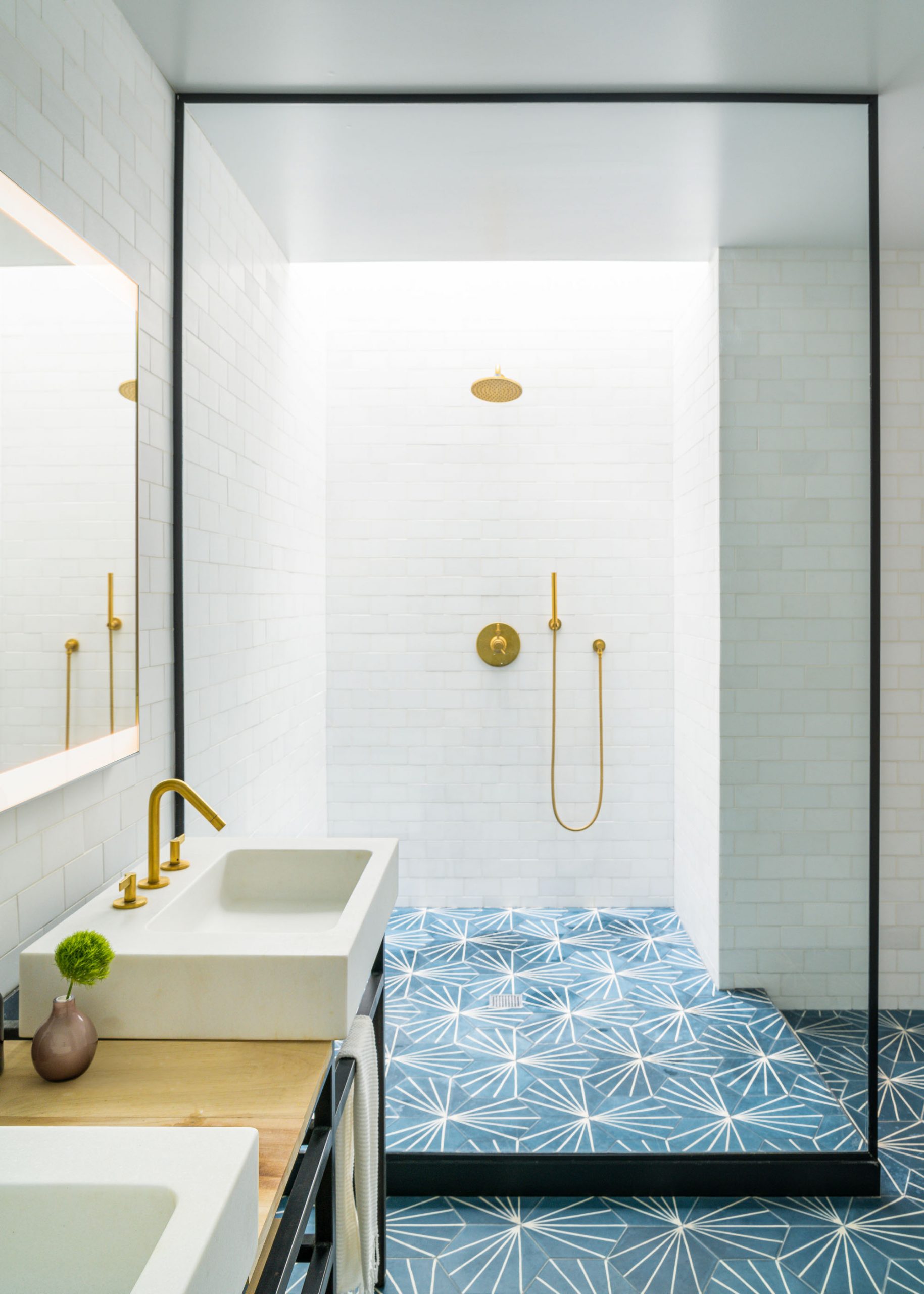 brightly lit shower with white tile and gold fixtures