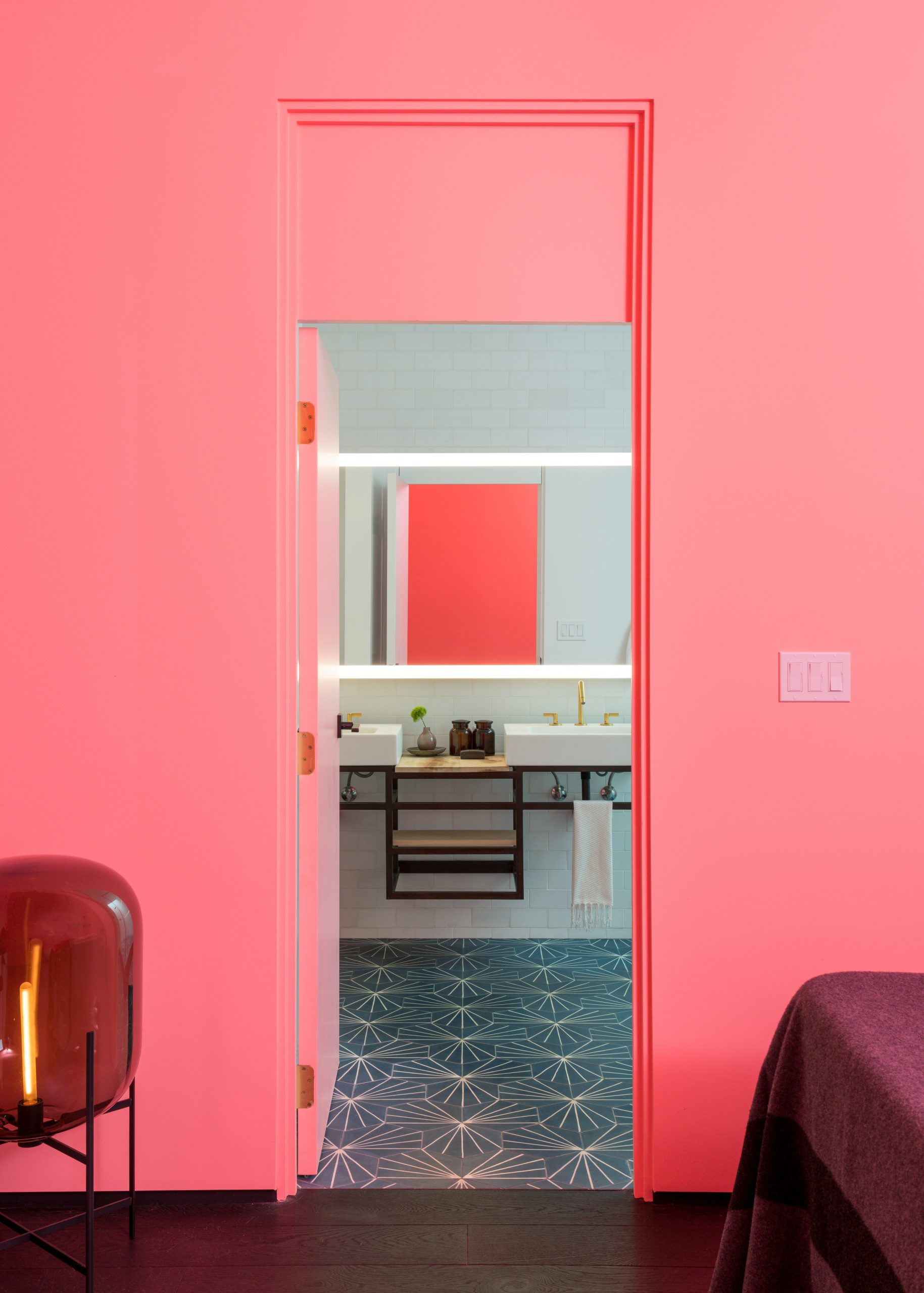 view through pink wall to bathroom with blue tile