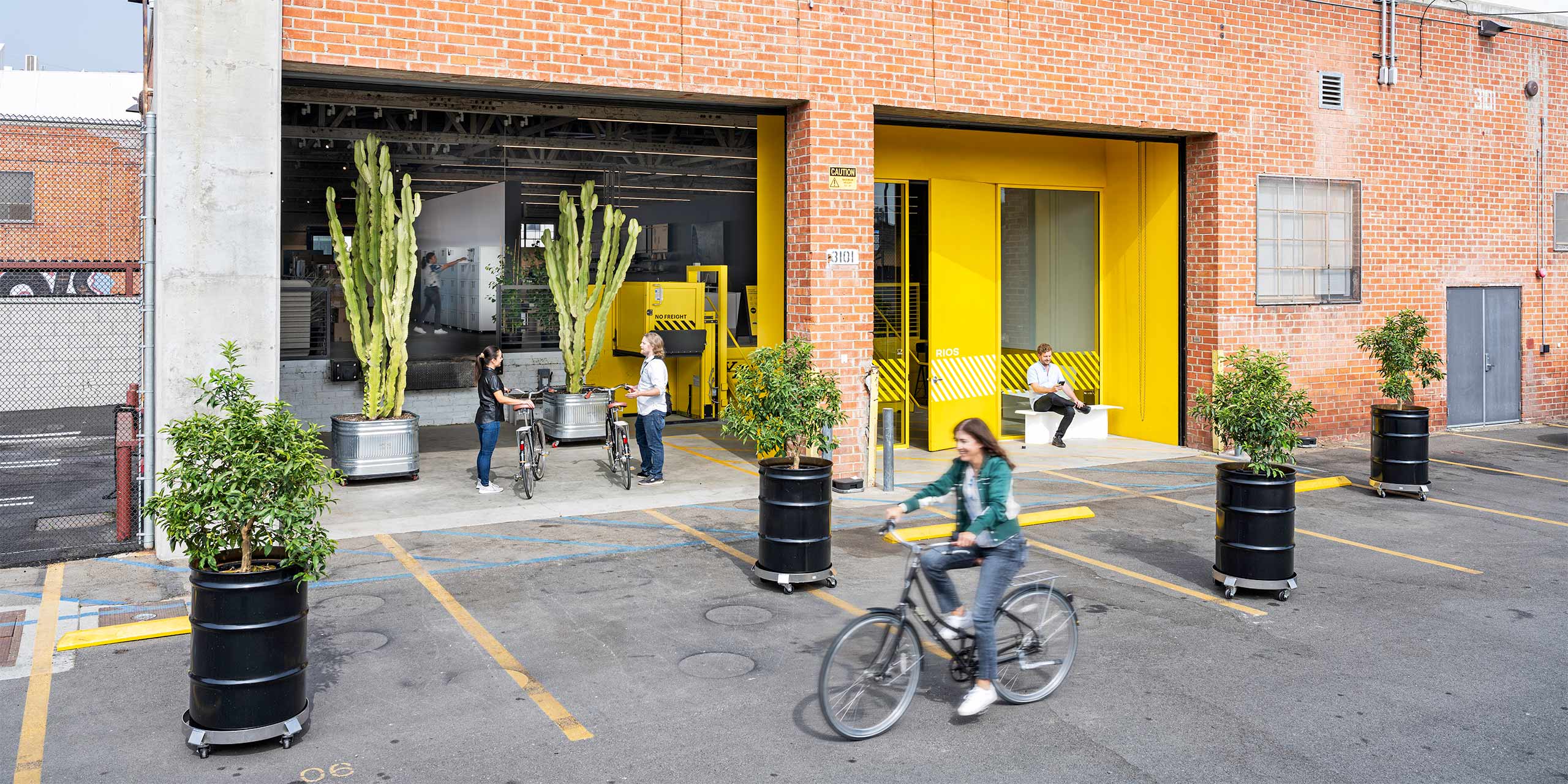 Exterior shot of the RIOS office with a woman riding her bike and cacti in the background