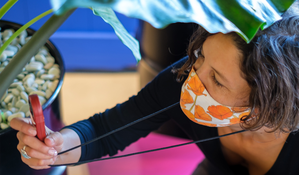 close up shot of a woman in a mask looking at a device hanging from her necklace