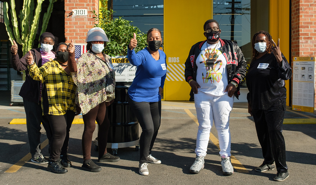 Los Angeles locals standing in front of the RIOS office wearing masks and giving a thumbs up