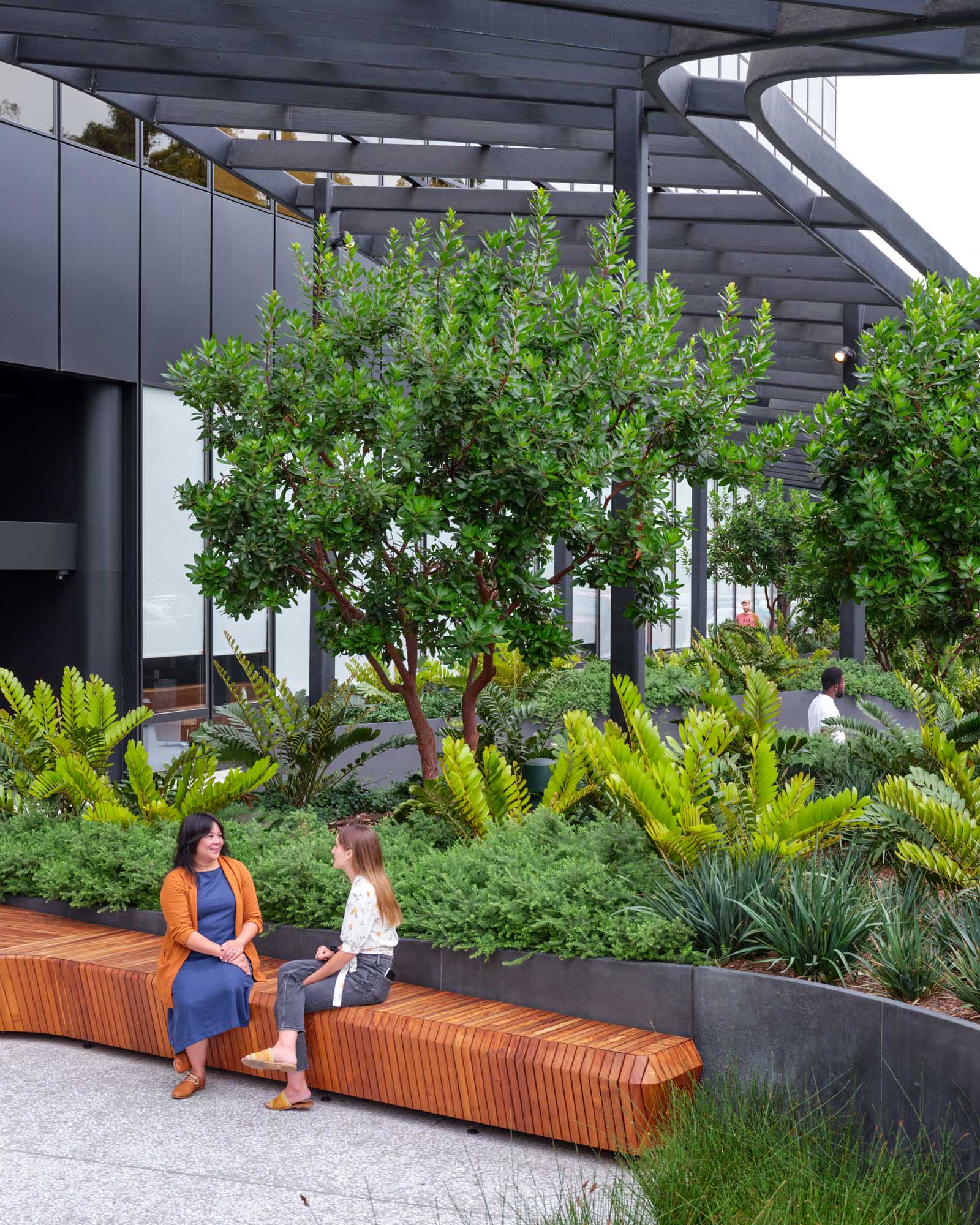 Women seated at a wooden bench surrounded by foliage