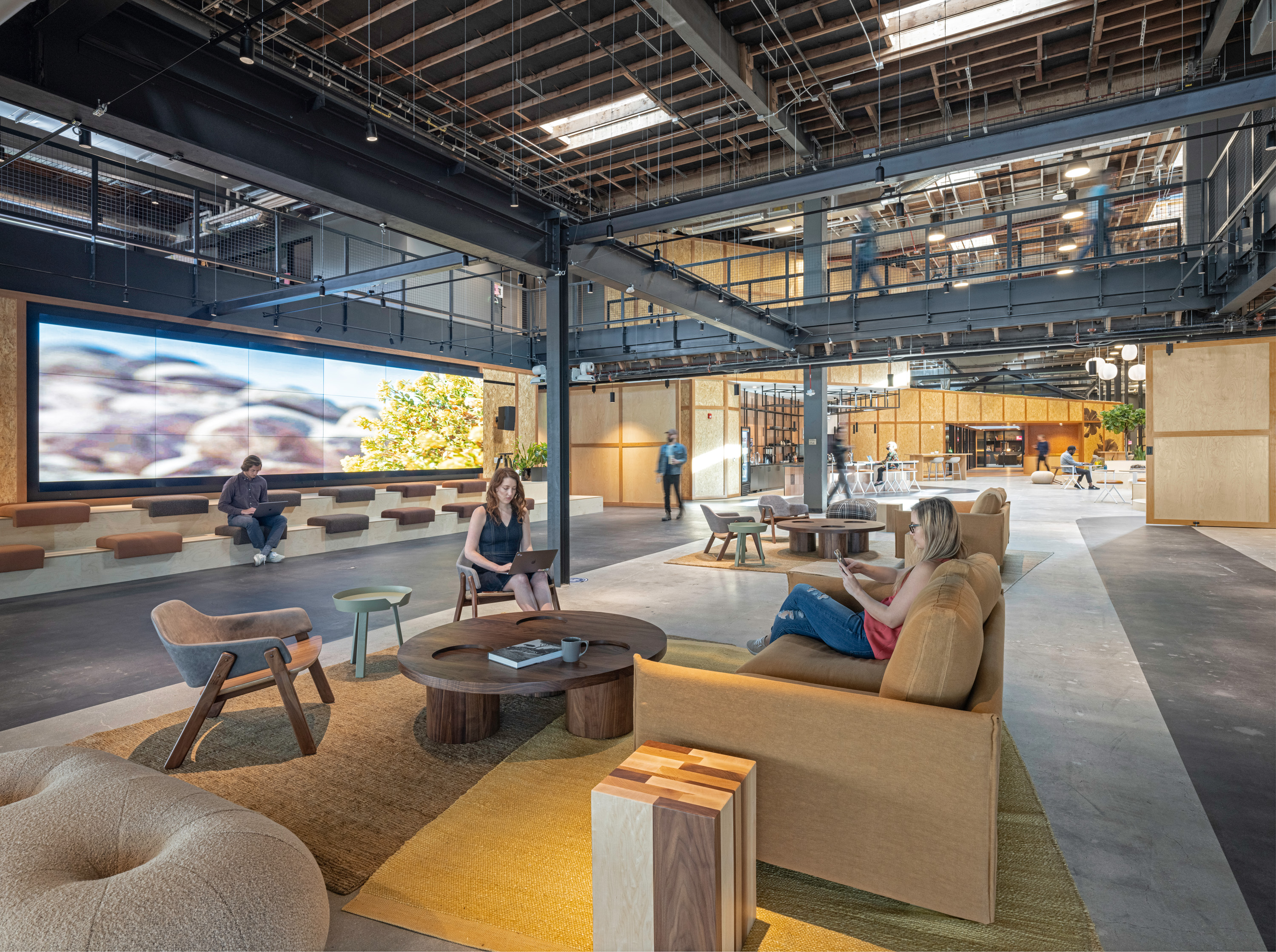 lounge and workplace area with comfortable seating with a wall to wall screen in the background