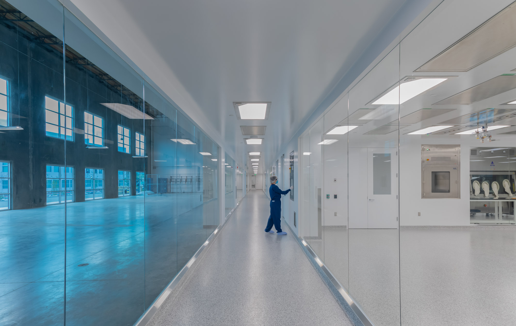 hallway view with glass windows on both sides revealing the laboratory space