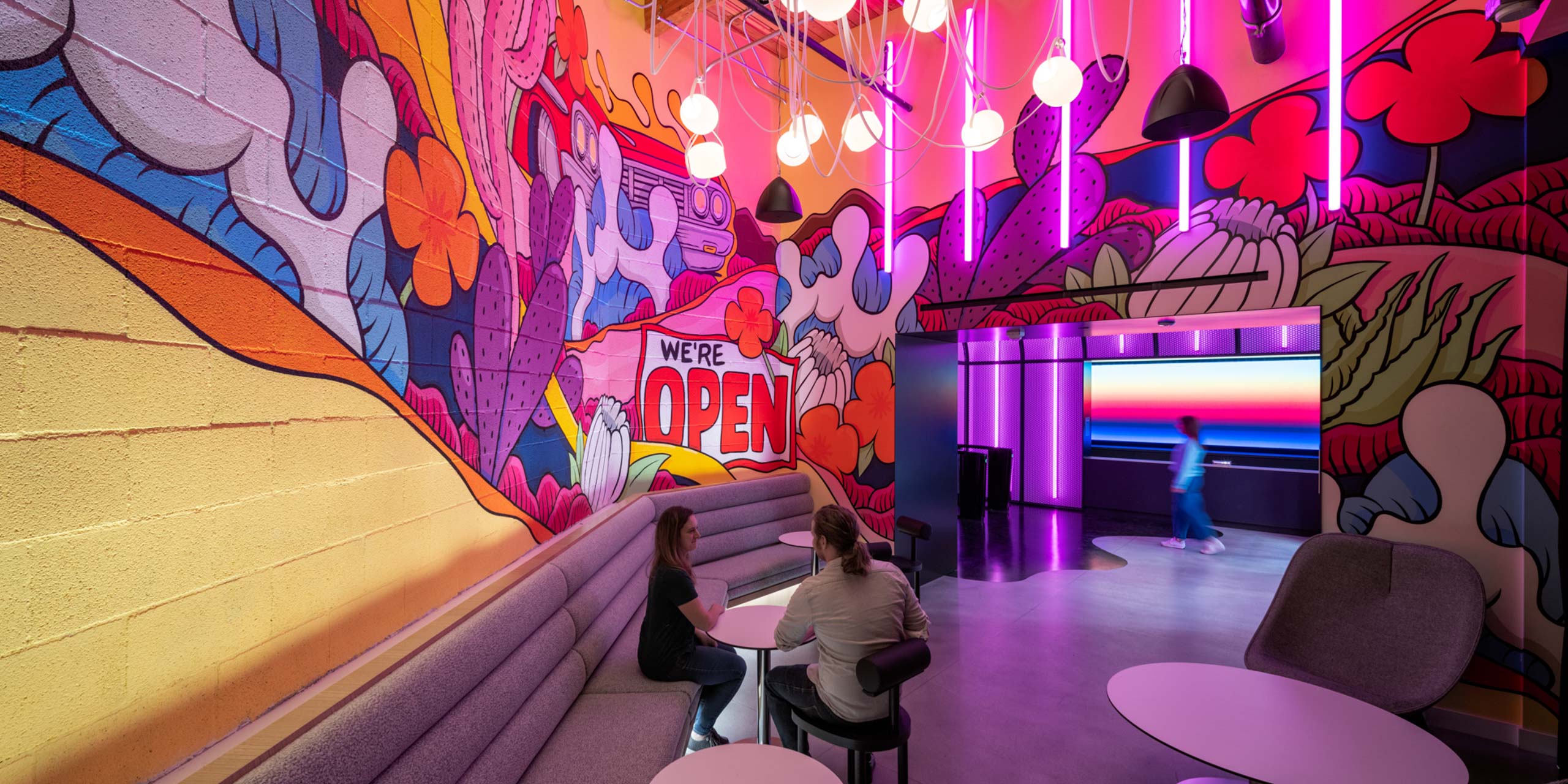 Lounge area with colorful painted wall mural and vibrant lights at Spotify