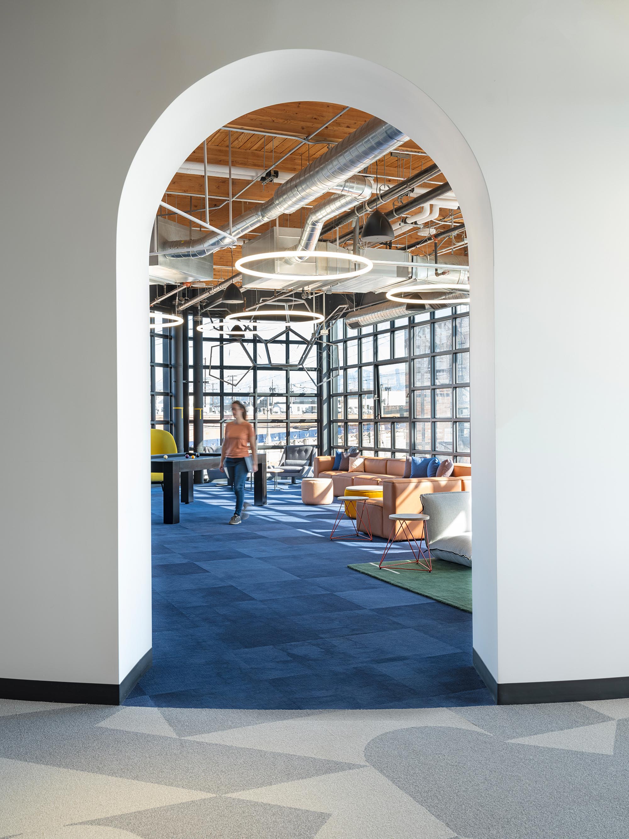 Arched entry looking into the interior workplace at Spotify with blue floors and colorful couches