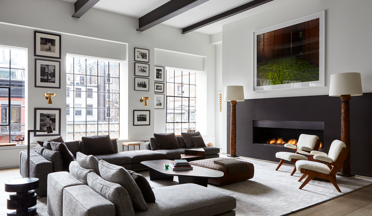 Interiors of New York loft with cozy couch next to fireplace and artwork on the walls