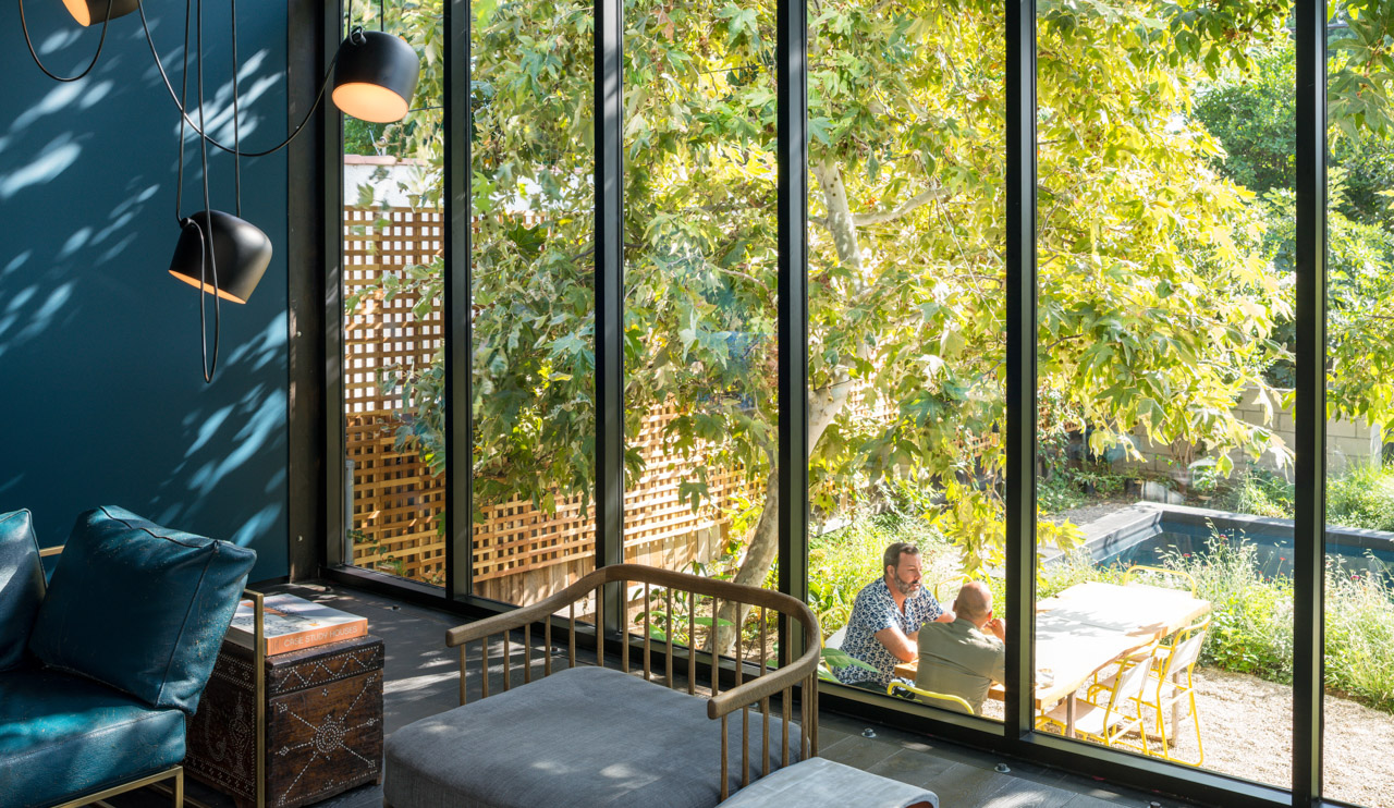 Interiors of living room with views out the floor to ceiling windows of the greenery in the backyard