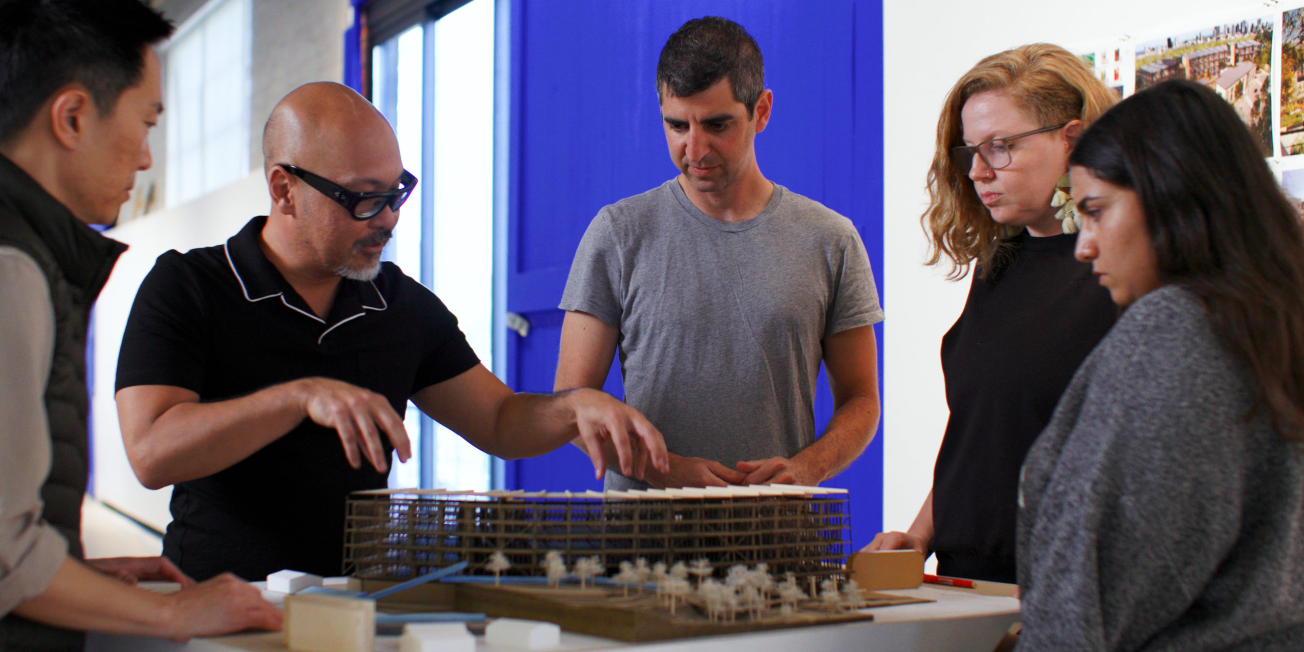 Five team members collaborating around an architectural model