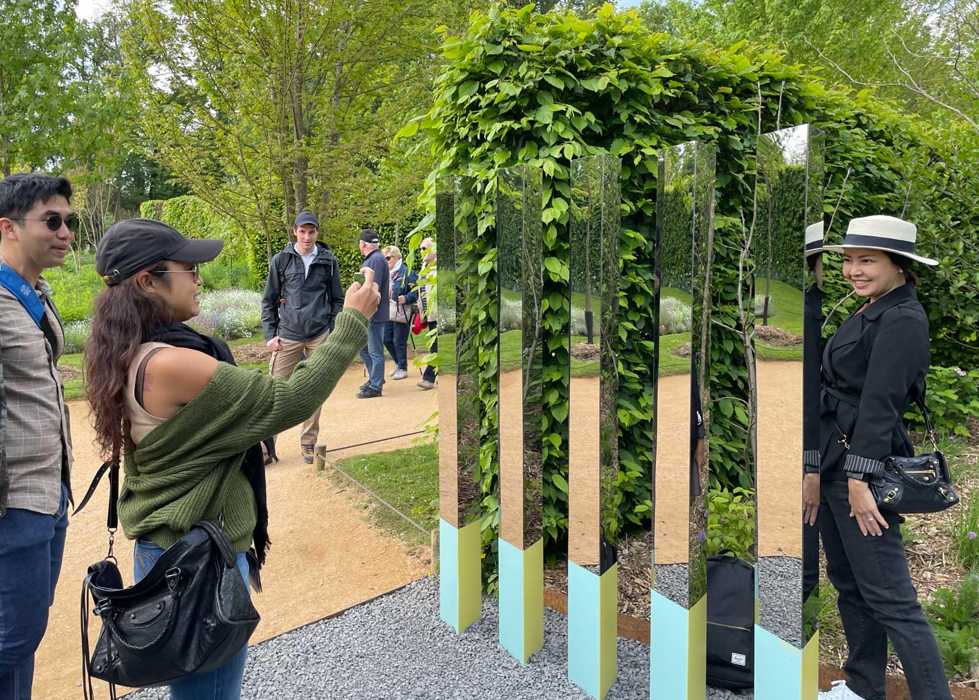 Person taking photos in front of mirrored totems at the Garden of Reciprocity