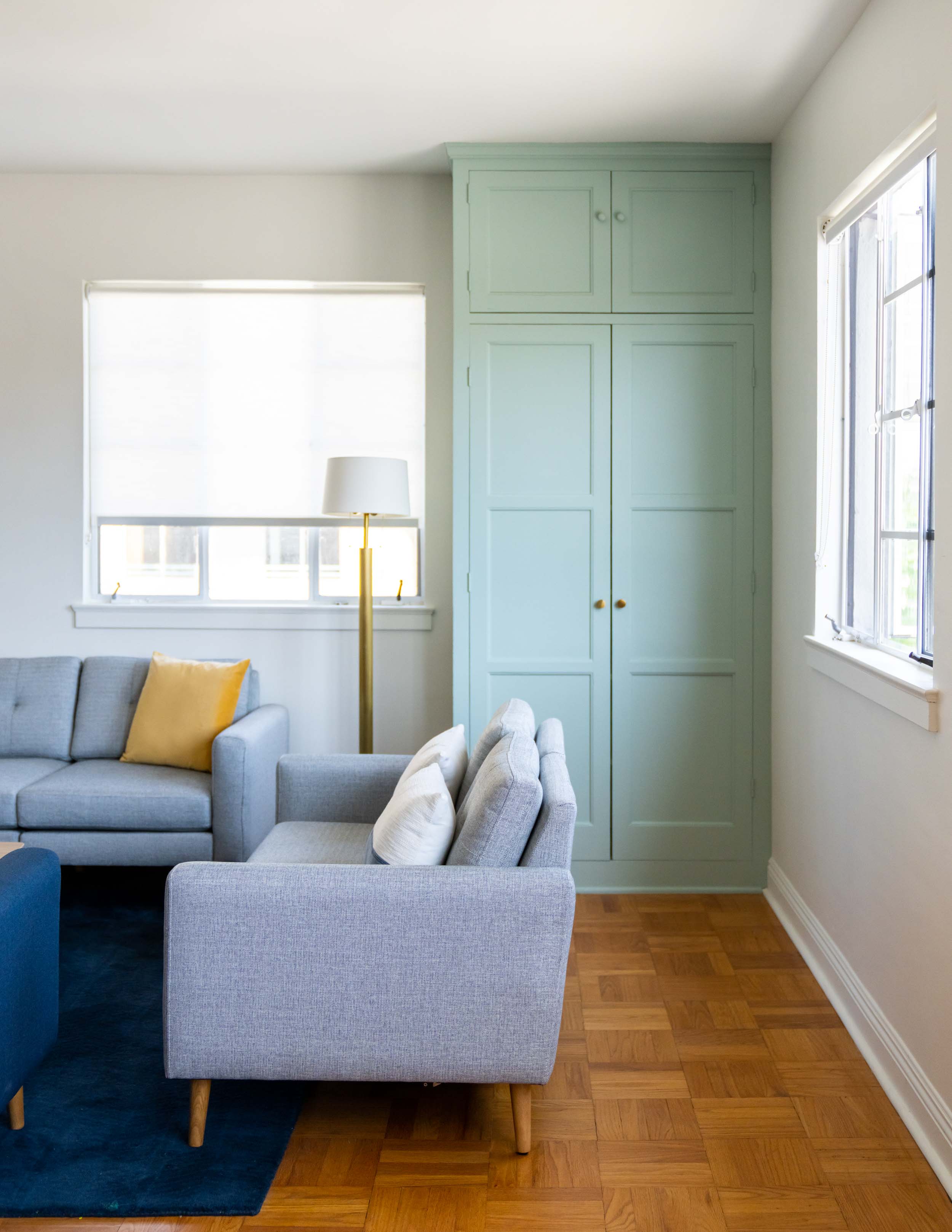 Detail of the grey couch, lamp, and blue cabinet