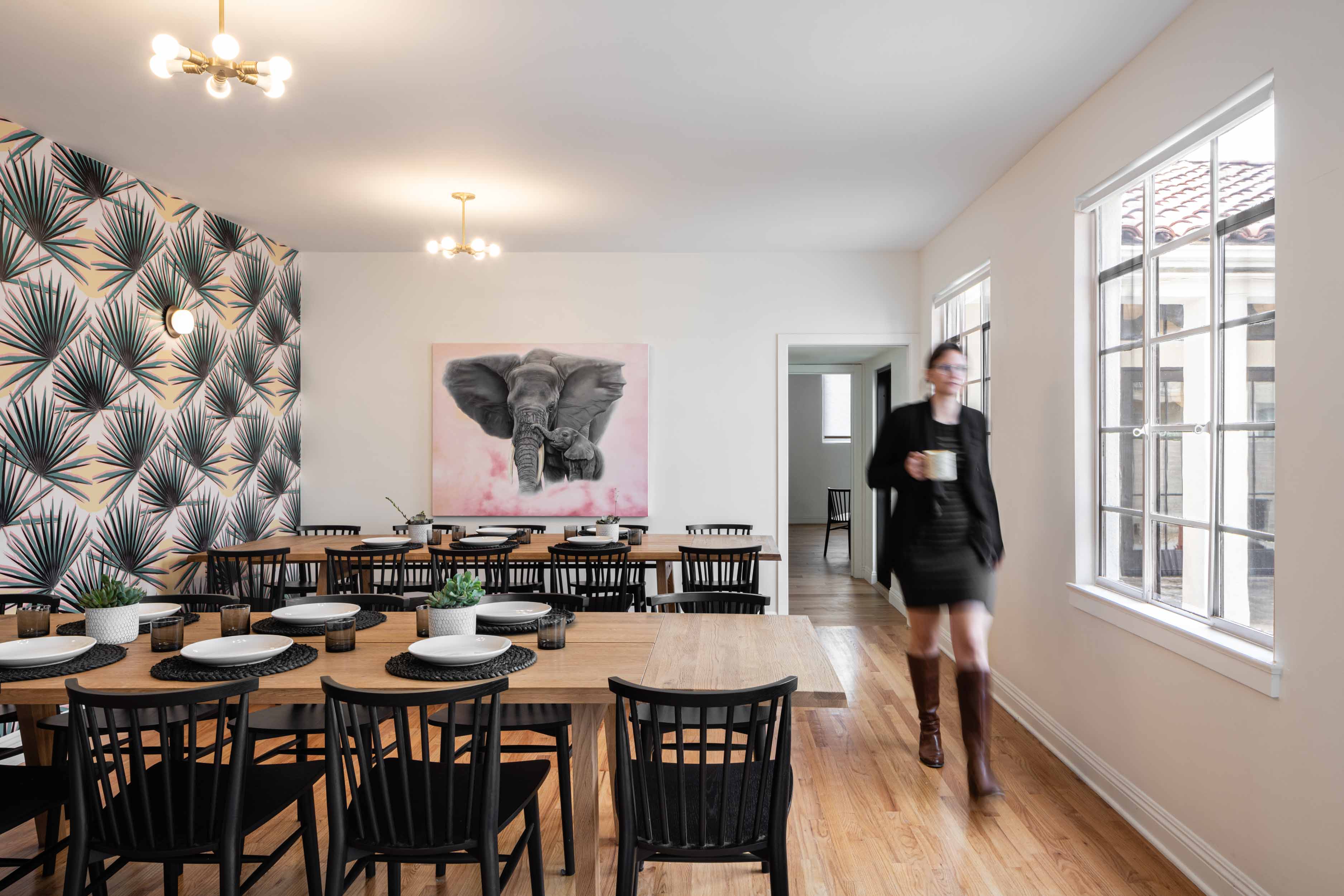 Woman walking into dining room with funky wallpaper and elephant art