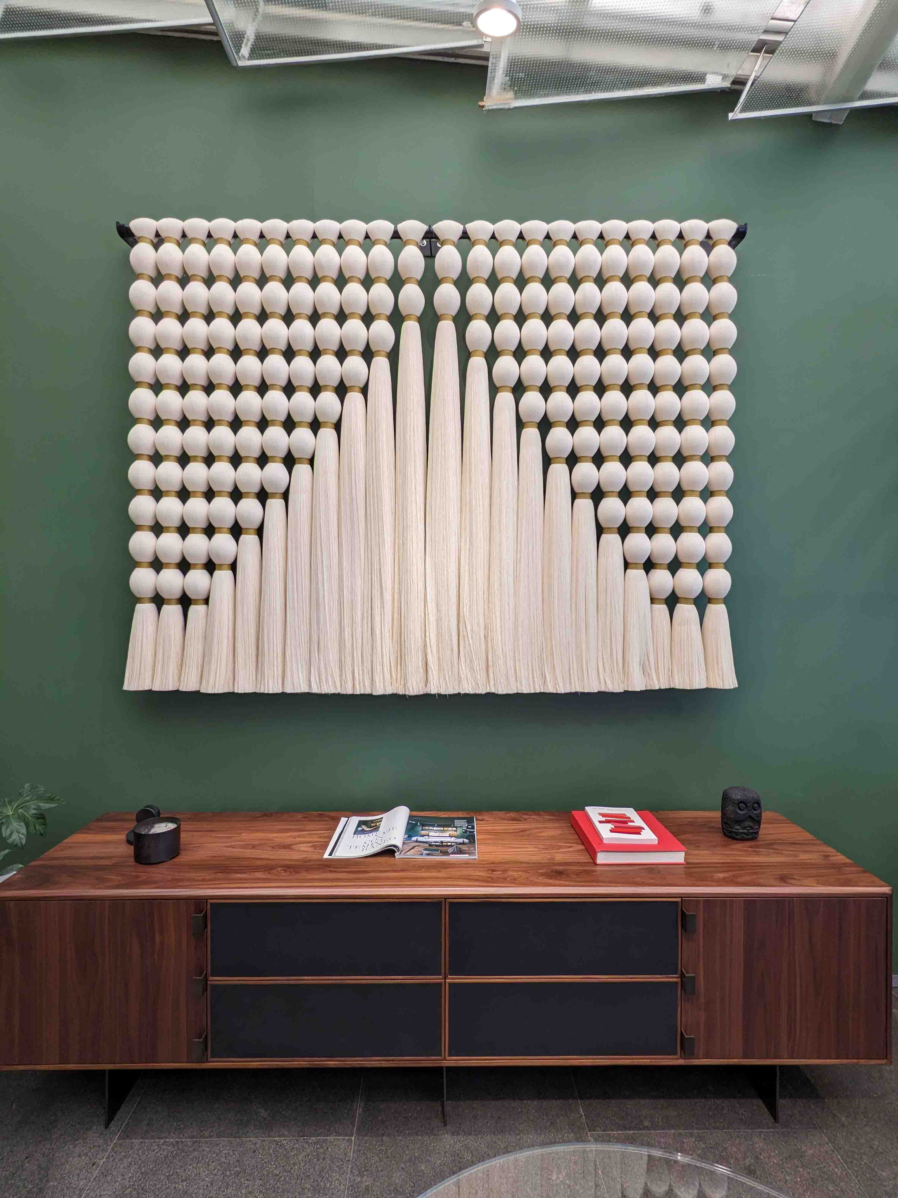 Wall hanging woven from repurposed cotton waste displayed over a wood credenza