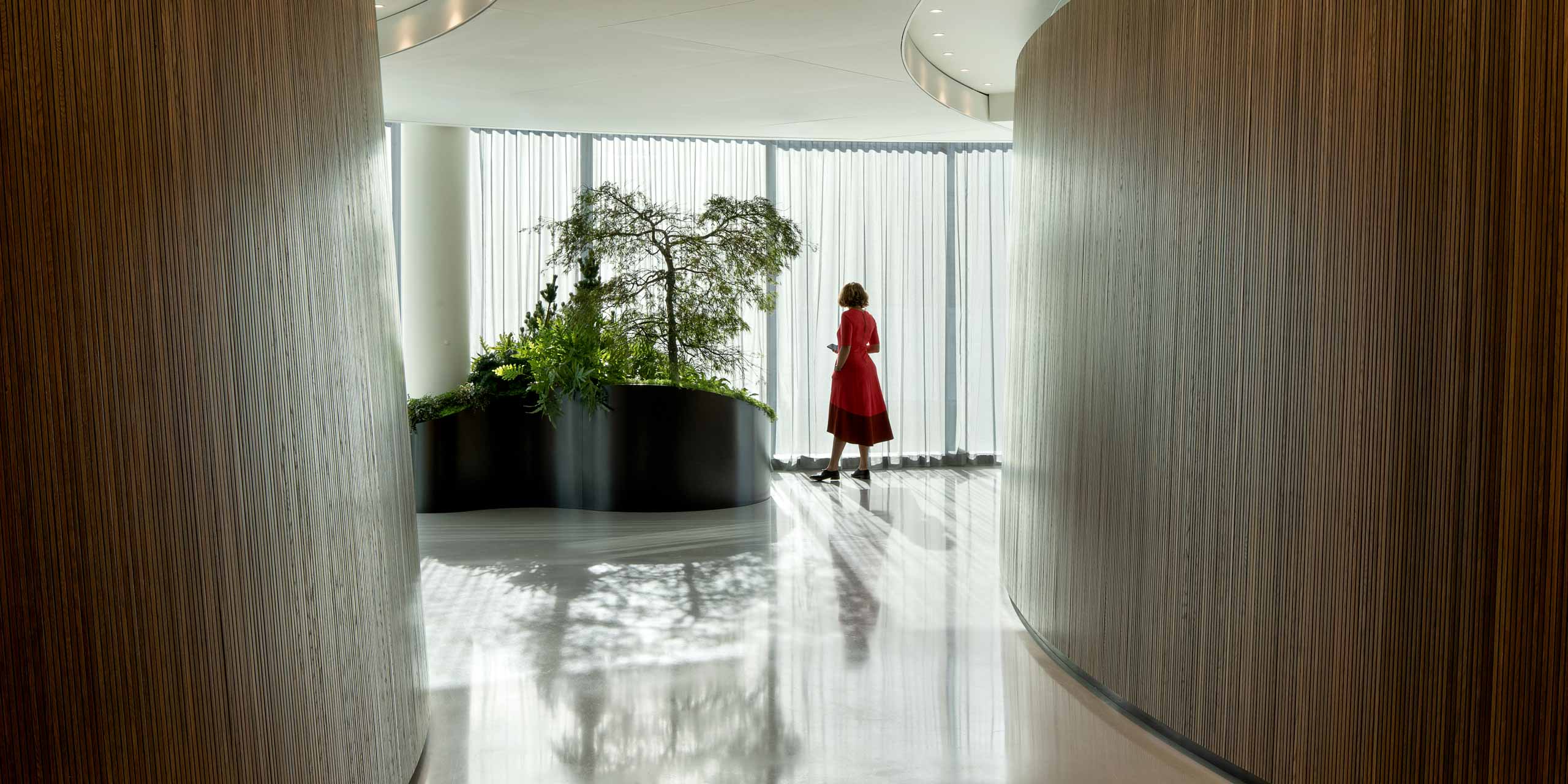 A woman in a red dress standing in a hallway.