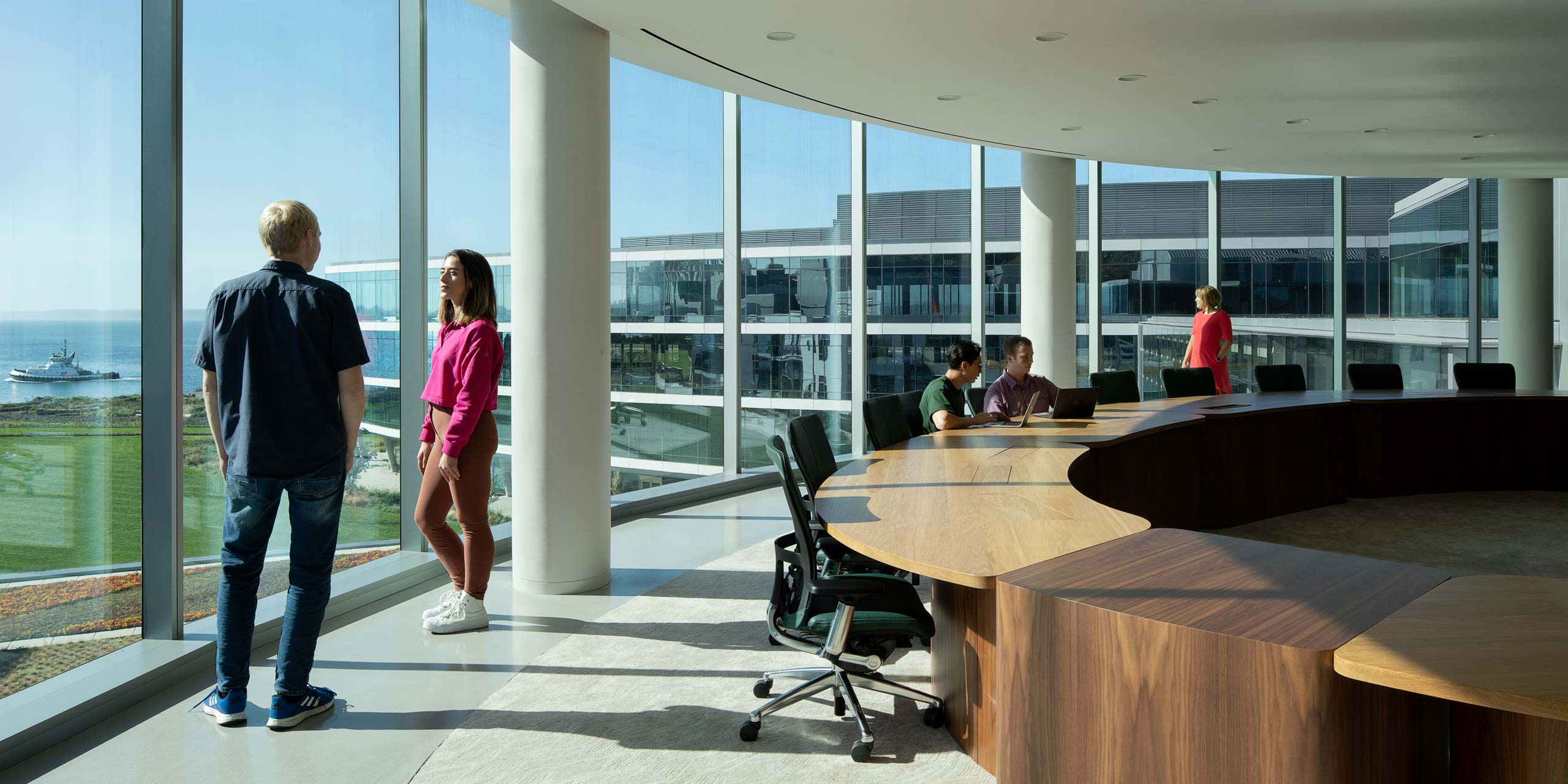 A group of people in the conference room with views to the river.