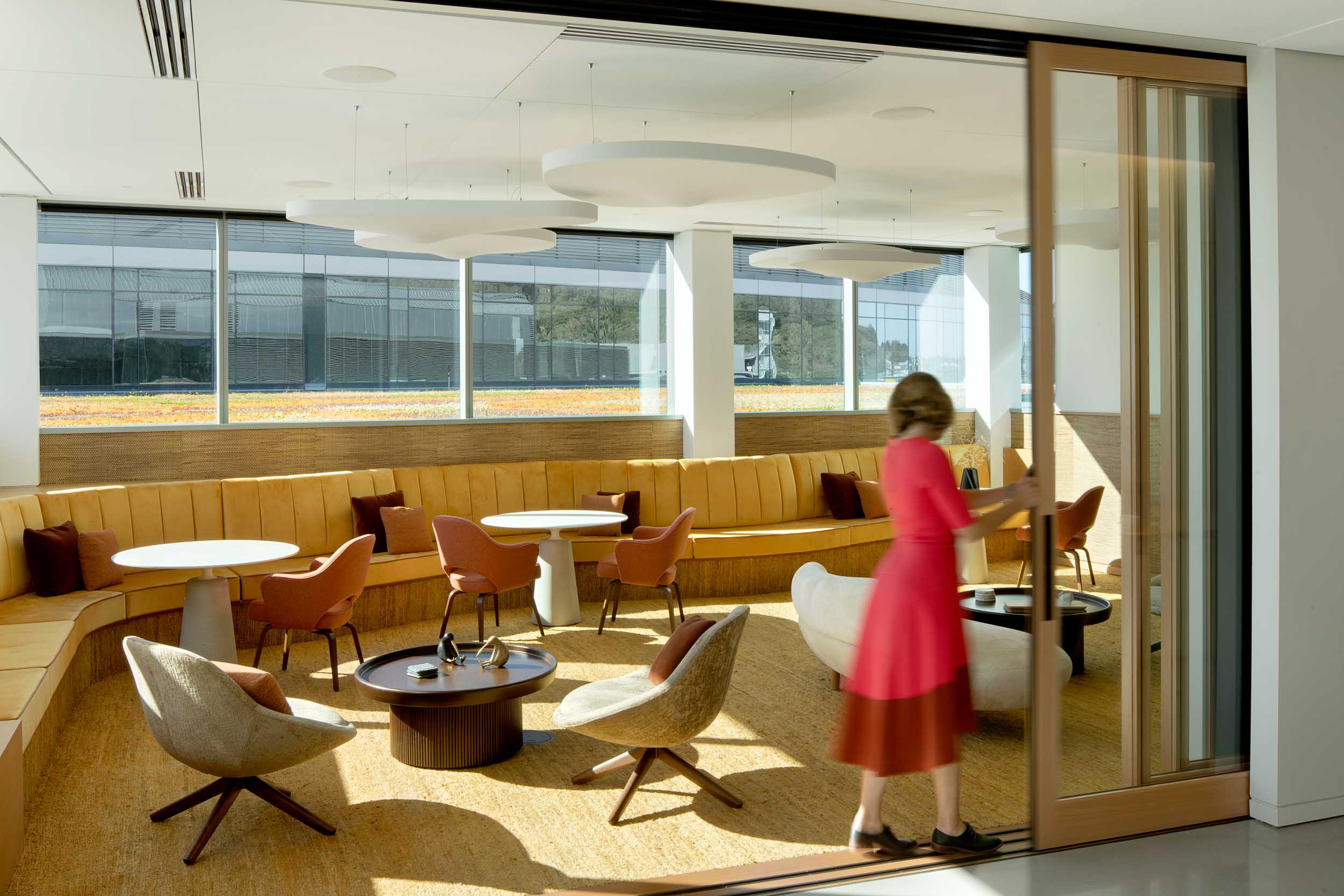 A woman in a red dress opening sliding doors to the office workspace.