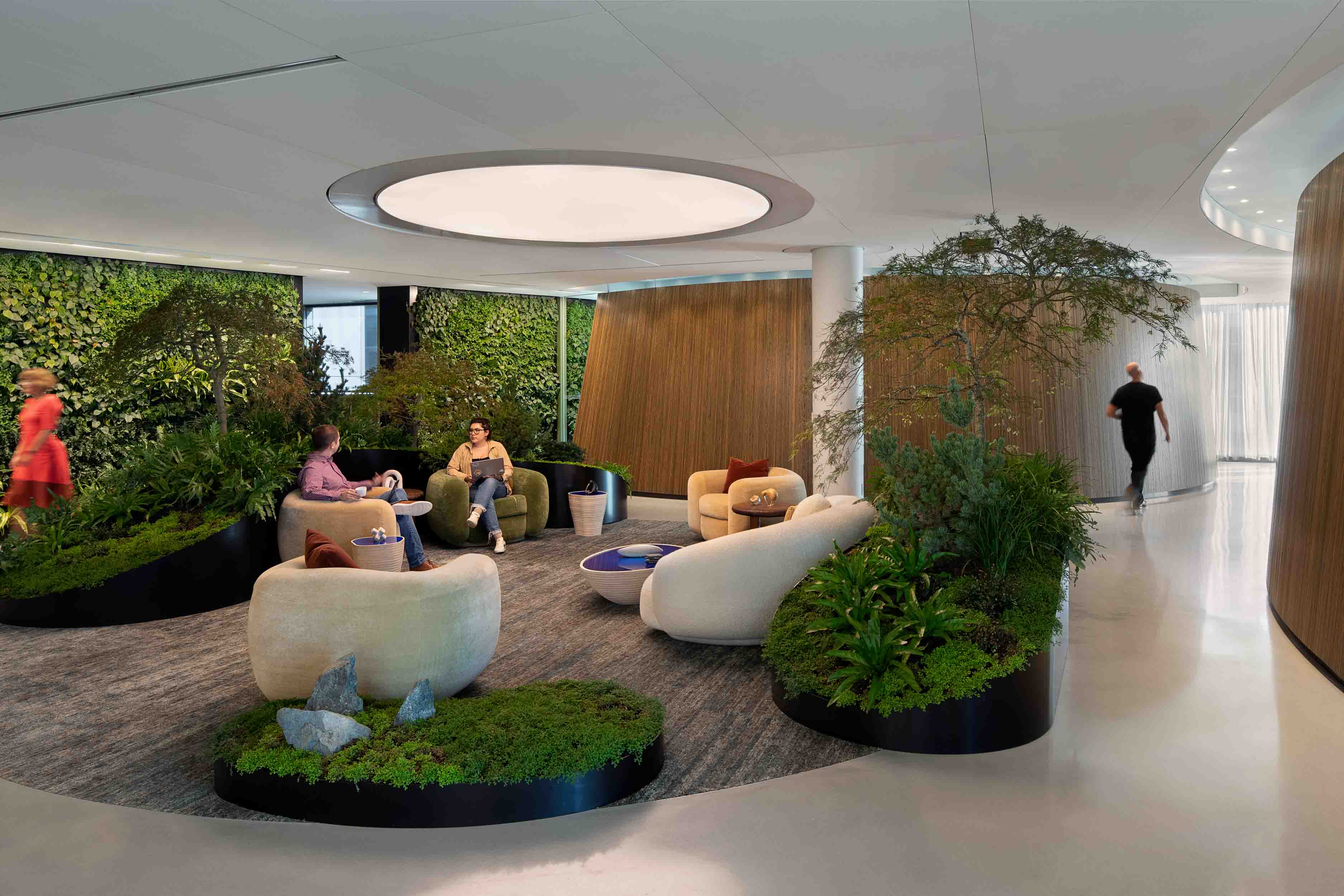 A group of people sitting around the central lounge space surrounded by interior gardens.