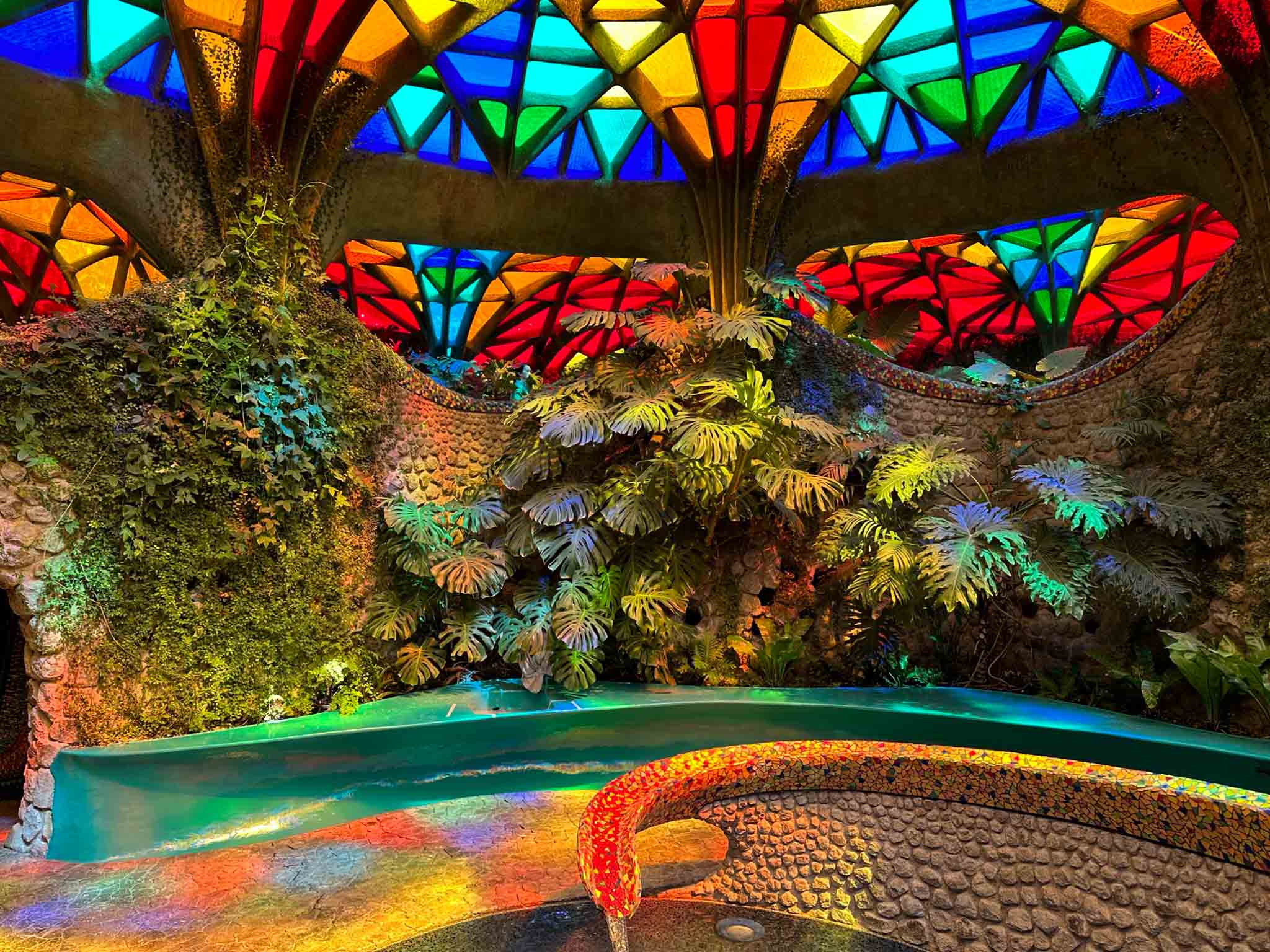 View of an interior garden under a brightly lit stained-glass ceiling