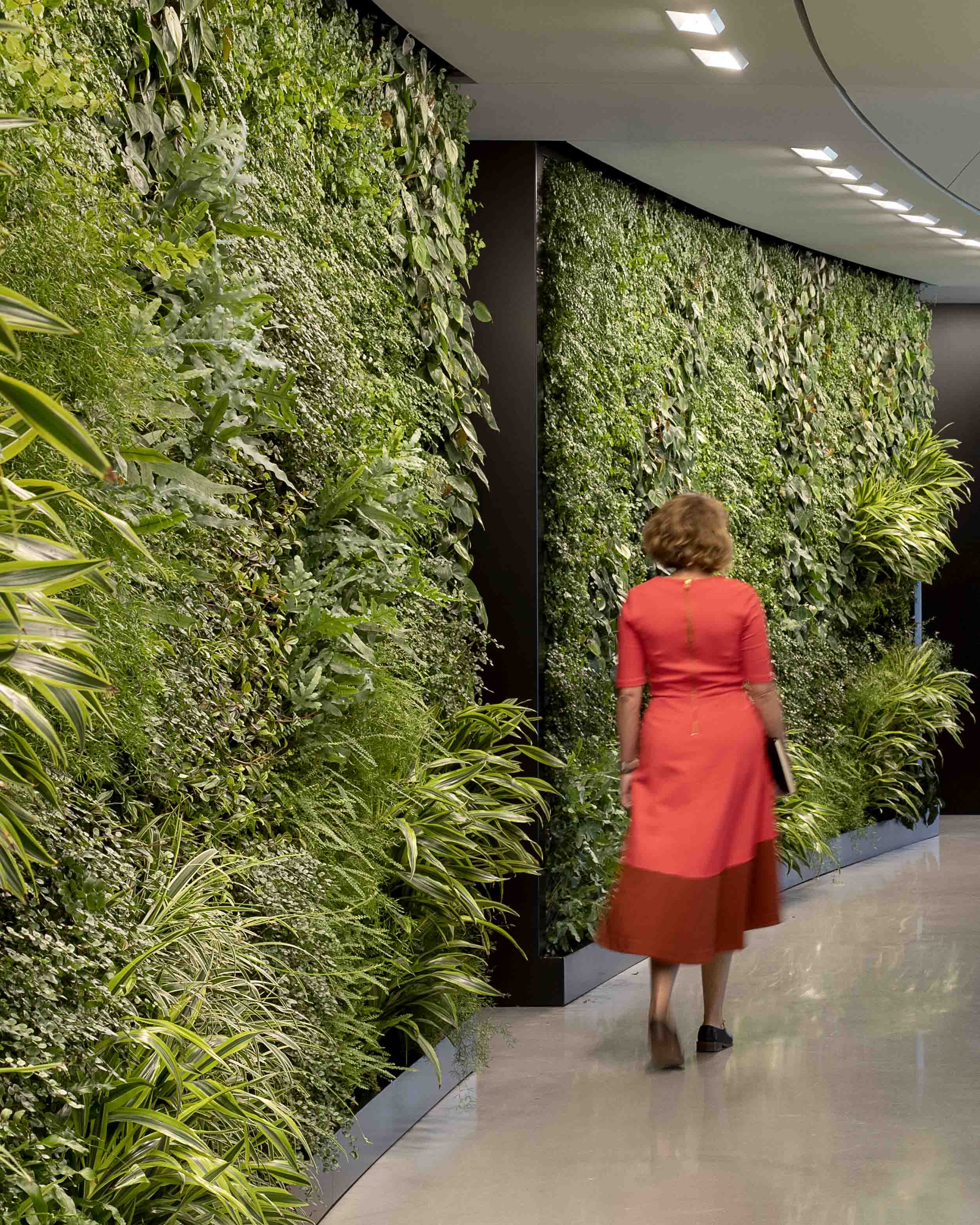 A woman in a red dress walking down a hallway.