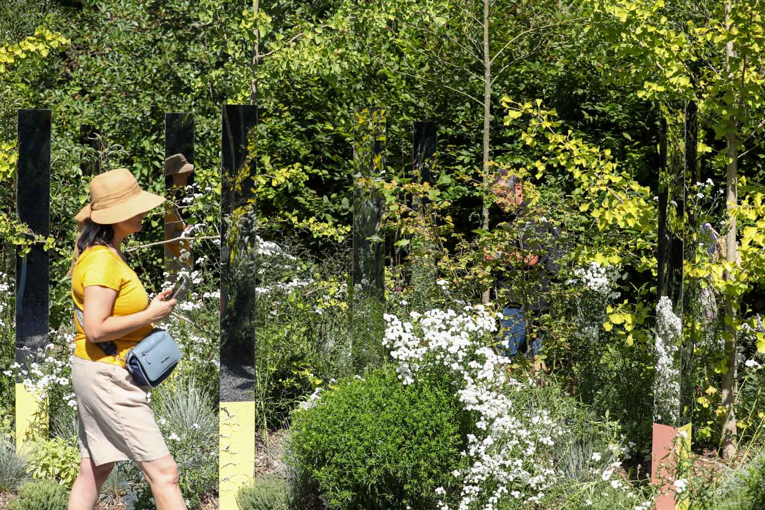 Photo of a woman walking through the lush plantings and mirrored prisms in the Garden of Reciprocity